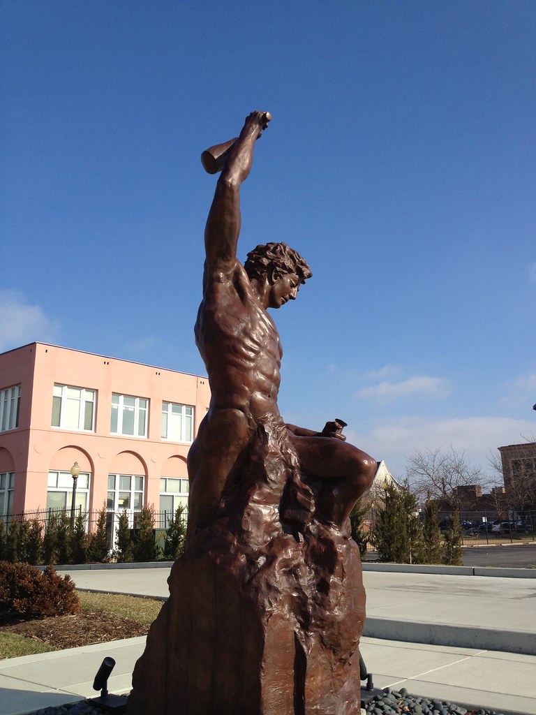 A imagem é uma foto da escultura da artista Bobbie Carlyle, que descreve o self-made man, um homem lapidando a si mesmo para fora da pedra bruta.