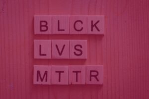 A imagem mostra peças de palavras cruzadas formando as palavras "BLCK LVS MTTR", abreviação da frase "Black Lives Matter", "Vidas Negras Importam' em português.