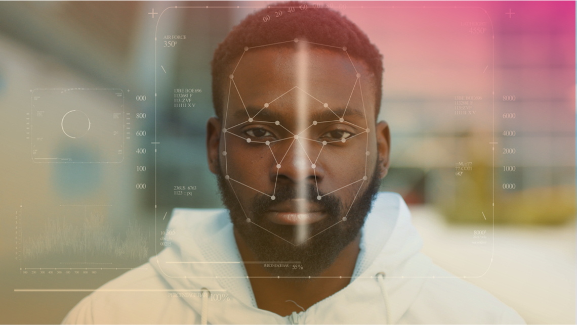 A imagem mostra um homem negro olhando para frente, com linhas que representam códigos de reconhecimento facial em primeiro plano.