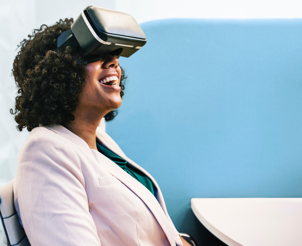 Na imagem, uma mulher negra sorri com um óculos de VR sendo usado.