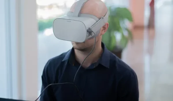 Na imagem, um homem branco utiliza um óculos de realidade virtual.